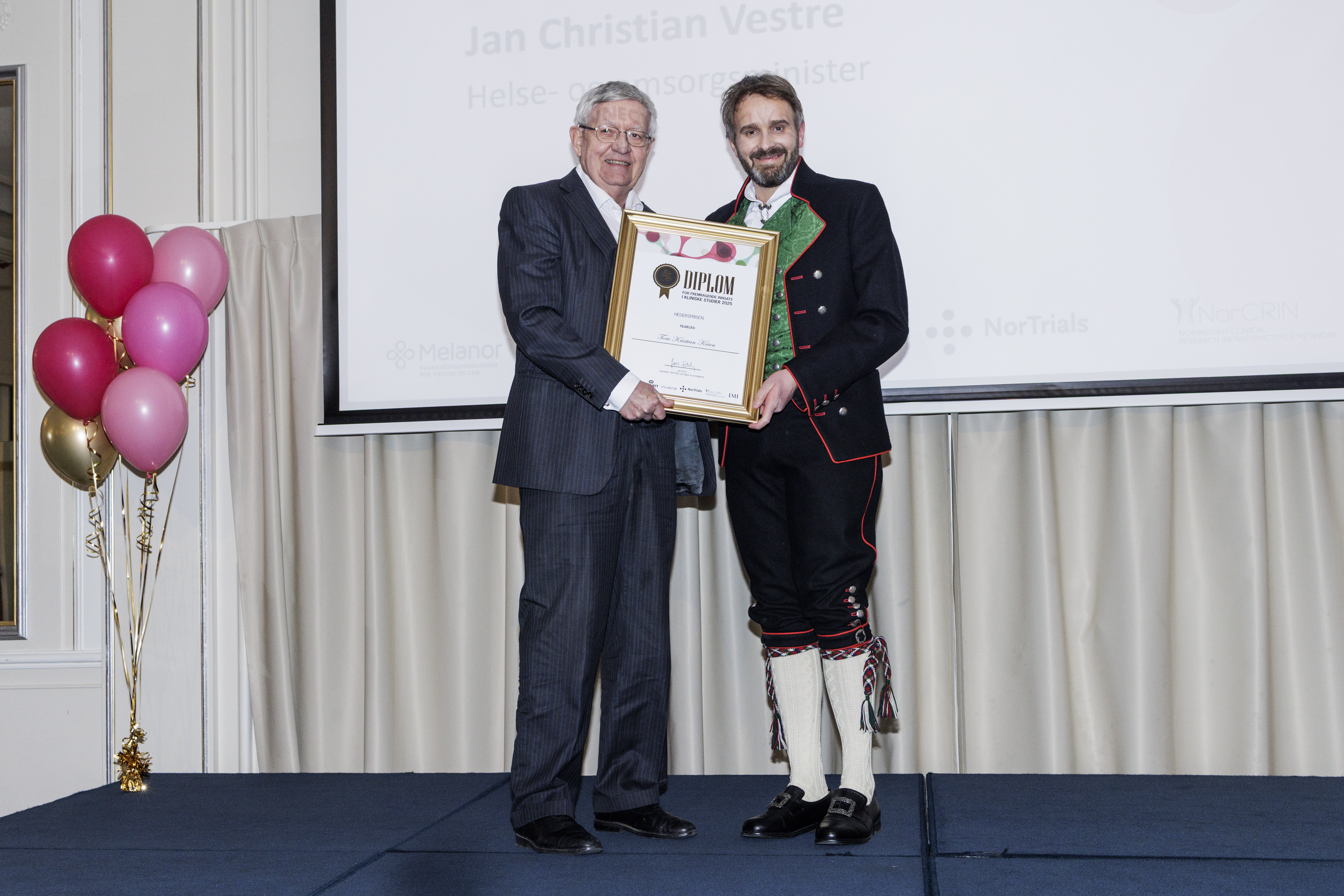 En person som holder et sertifikat ved siden av en person som holder en plakett