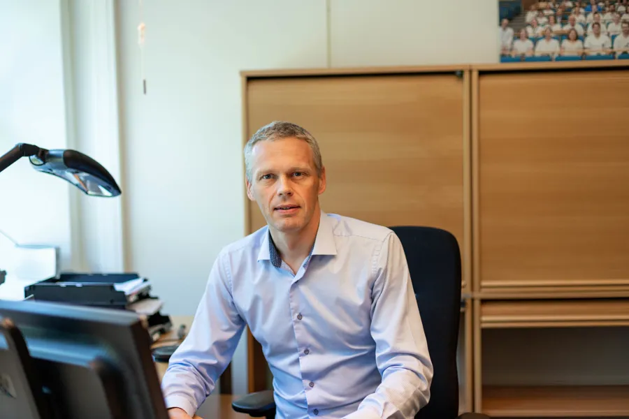 Fagdirektør i Helse Vest sitter i kontorstol med en arbeidspult
