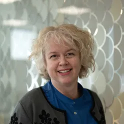 Kvinne ser i kamera og smiler