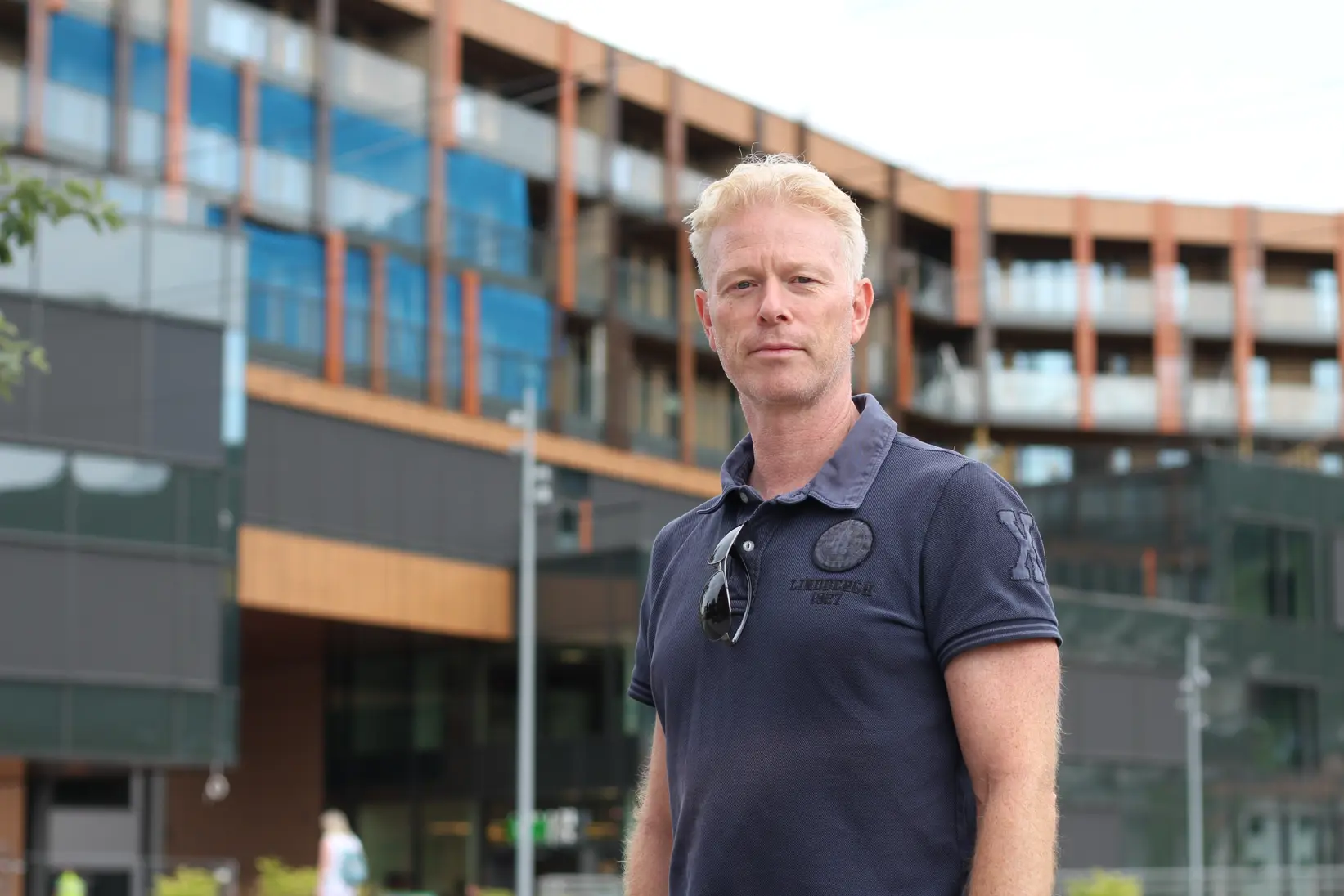 mann i t-skjorte utenfor stort bygg