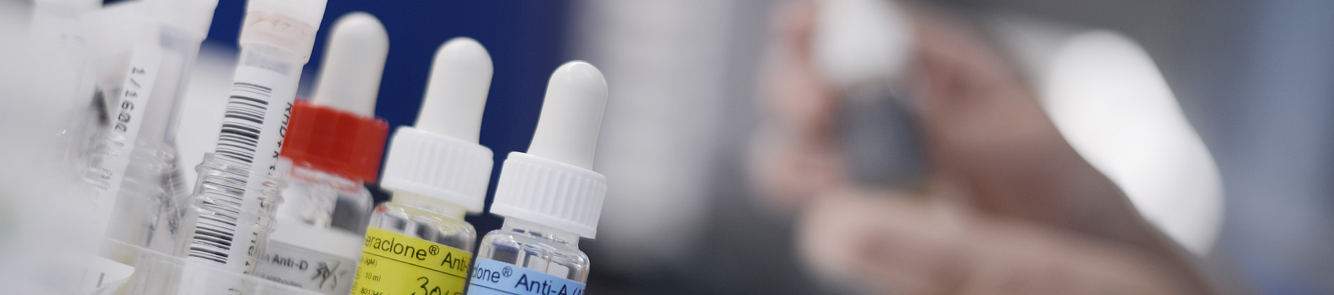A close-up of a hand holding a white tube with a yellow cap