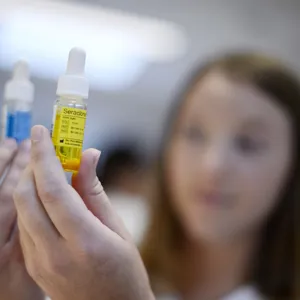 Dame som holder to medisinflasker. Foto.