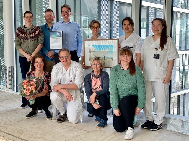 3 menn og 7 kvinner, med diplom og blomar og kunstverk. Foto.