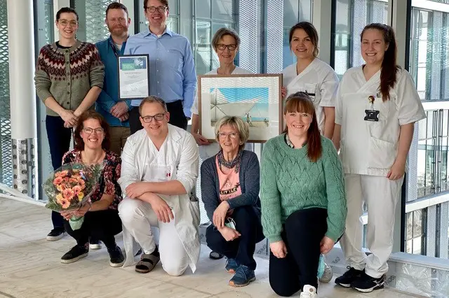 3 menn og 7 kvinner, med diplom og blomar og kunstverk. Foto.