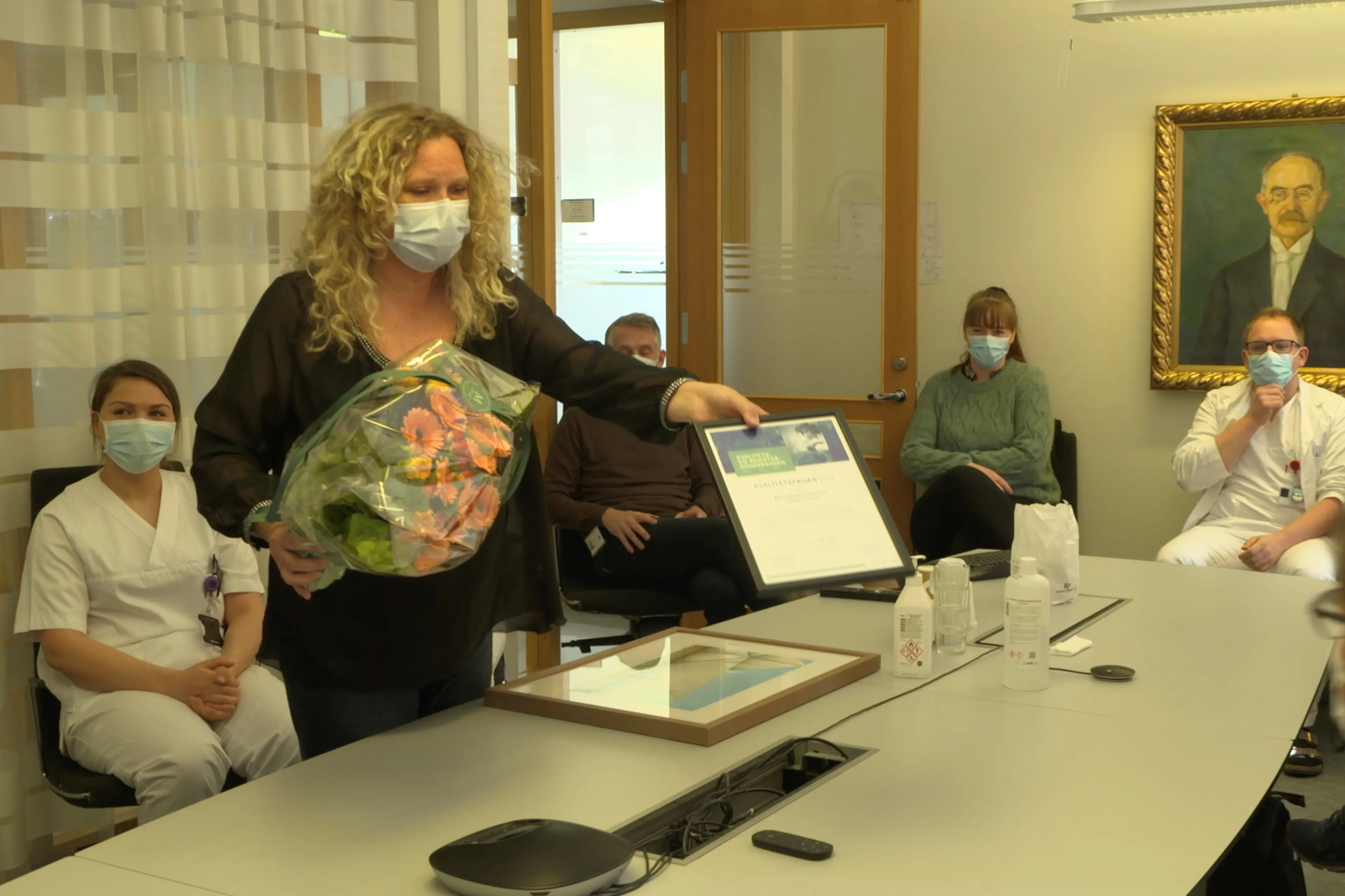 Helsepersonell i et møterom, får pris. Foto.