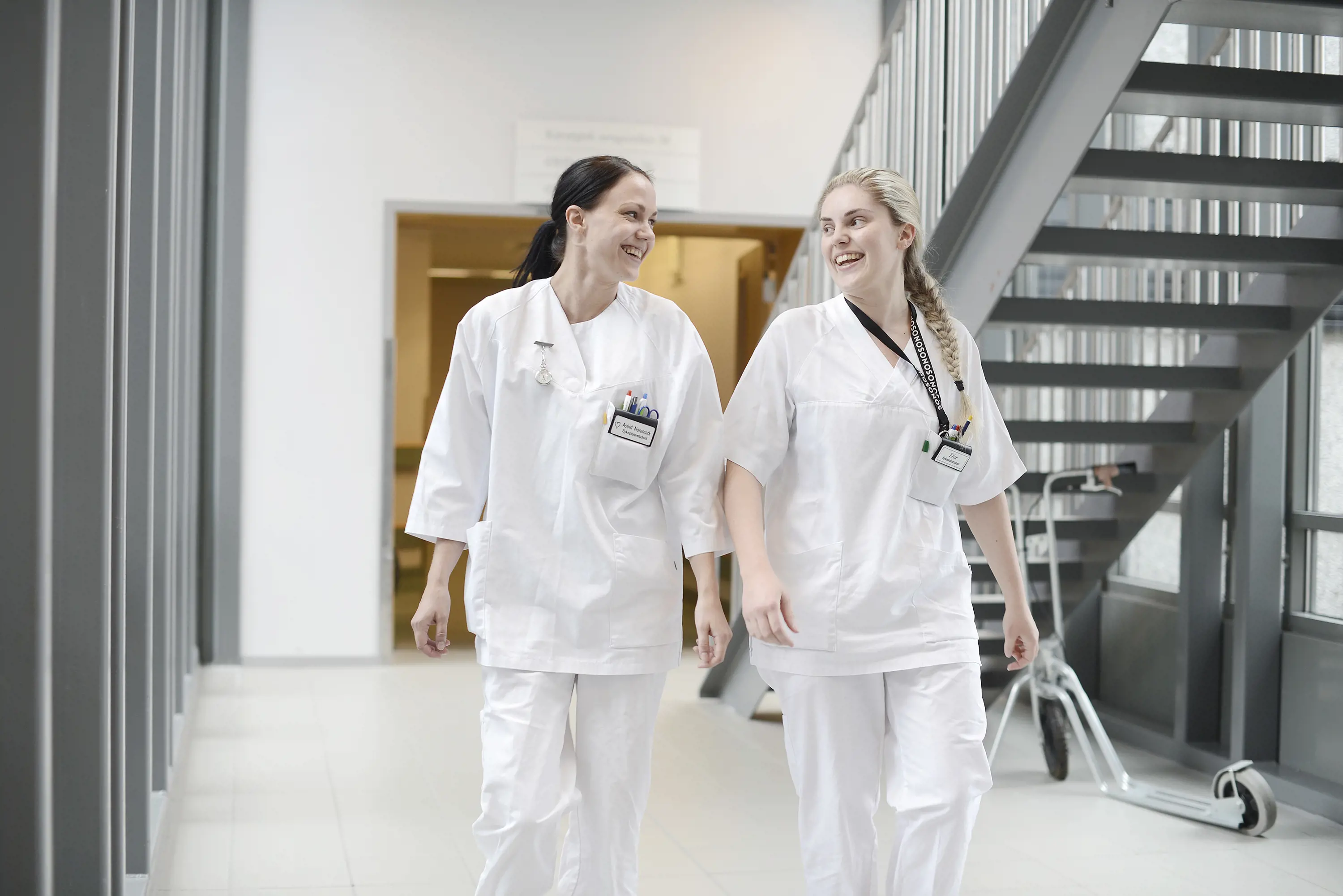 Two nurses walking in hospital hallway. Photo.