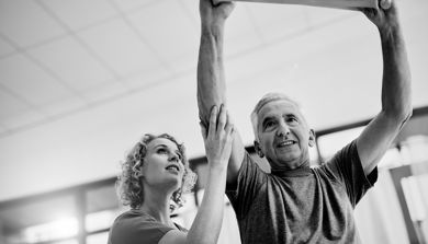 Svart hvitt foto sykepleier hjelper eldre mann med trening