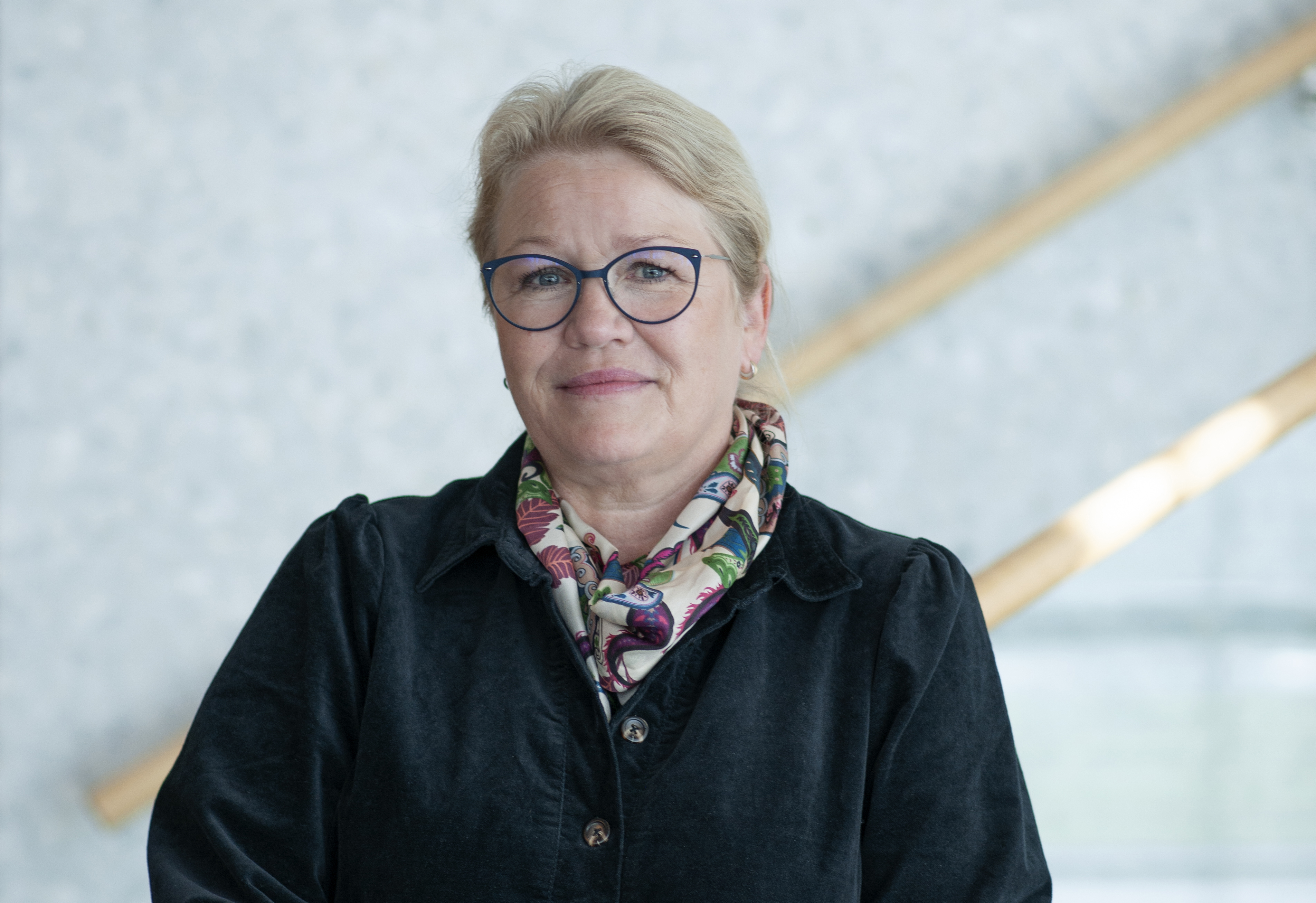 Dame med briller smiler i kamera. Foto