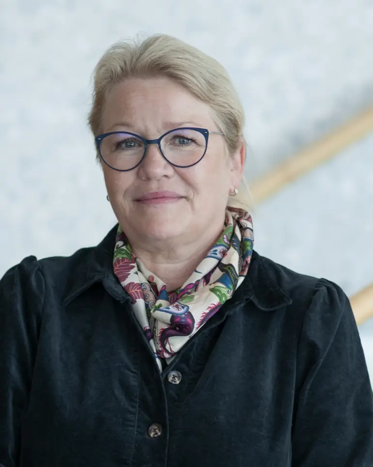 Dame med briller smiler i kamera. Foto