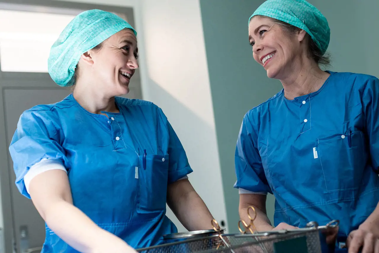 To kvinner i blå klær, smiler. Helsepersonell. Foto.