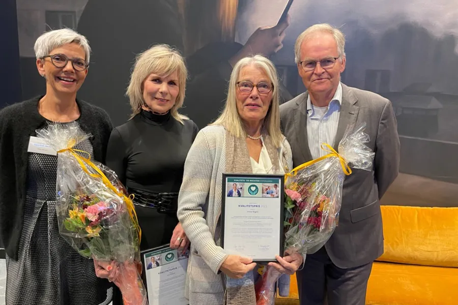 Fire personar med diplom og blomar. Vinnarar Kvalitetsprisen 2022. Foto.
