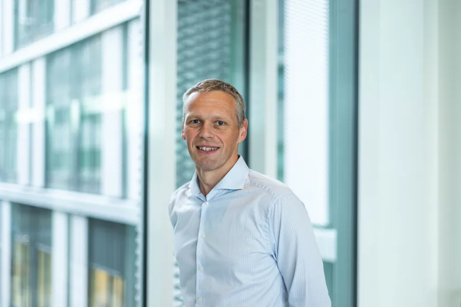 Mann i lyseblått skjorte, smiler i kameraet.