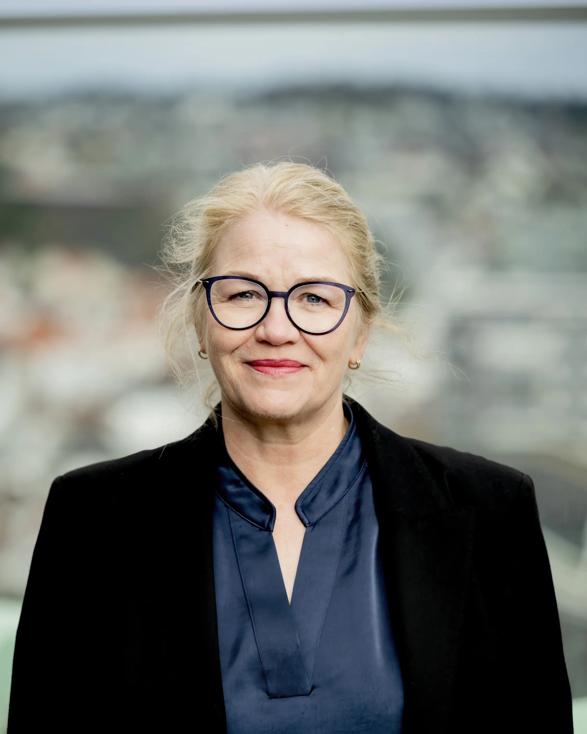 Dame med briller står ute og ser mot kamera