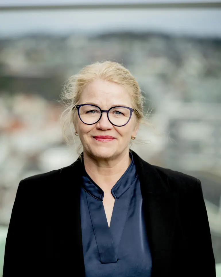 Dame med briller står ute og ser mot kamera