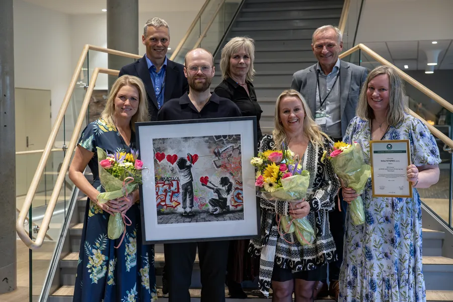 En gruppe mennesker som holder blomster og et innrammet bilde