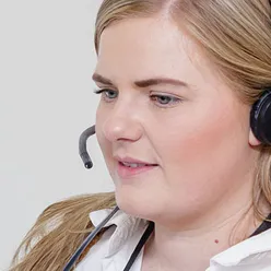 Kvinne med headset foran PC. Foto.