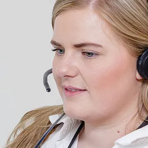 Kvinne med headset foran PC. Foto.