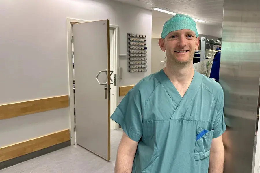 En mann iført en scrubs og en blå skjorte