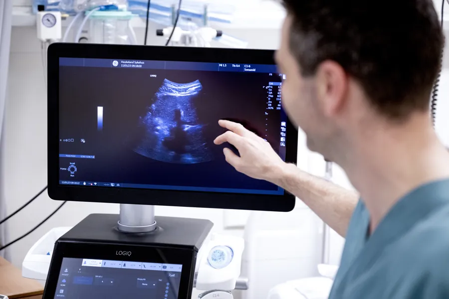 Helsepersonell ser på eit bilde på ein skjerm. Foto.