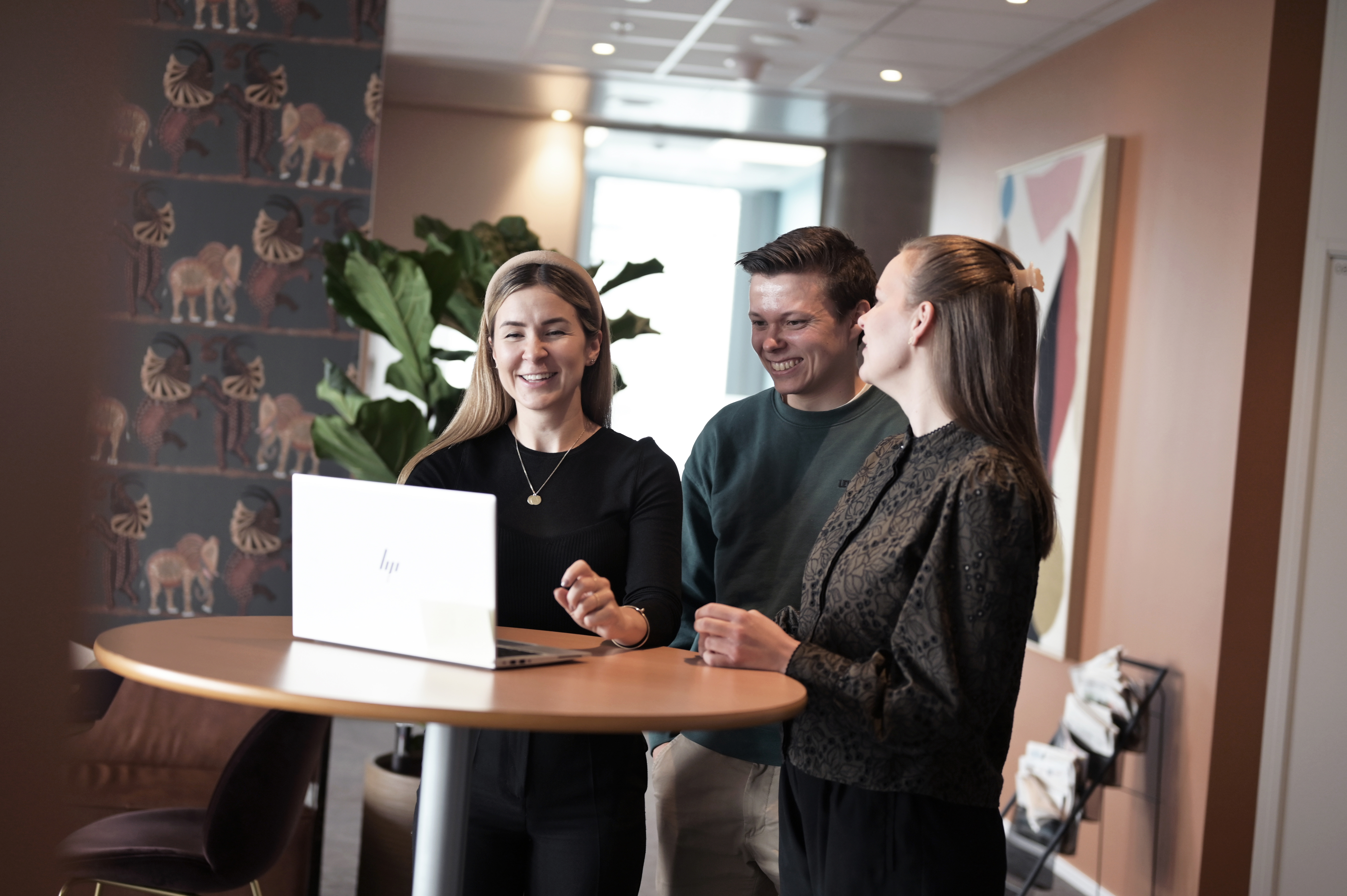 Tre personer bak et bord med en PC