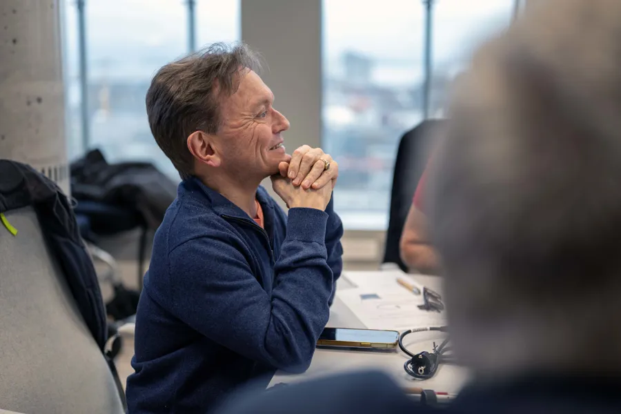 En mann som sitter smilende ved et skrivebordet