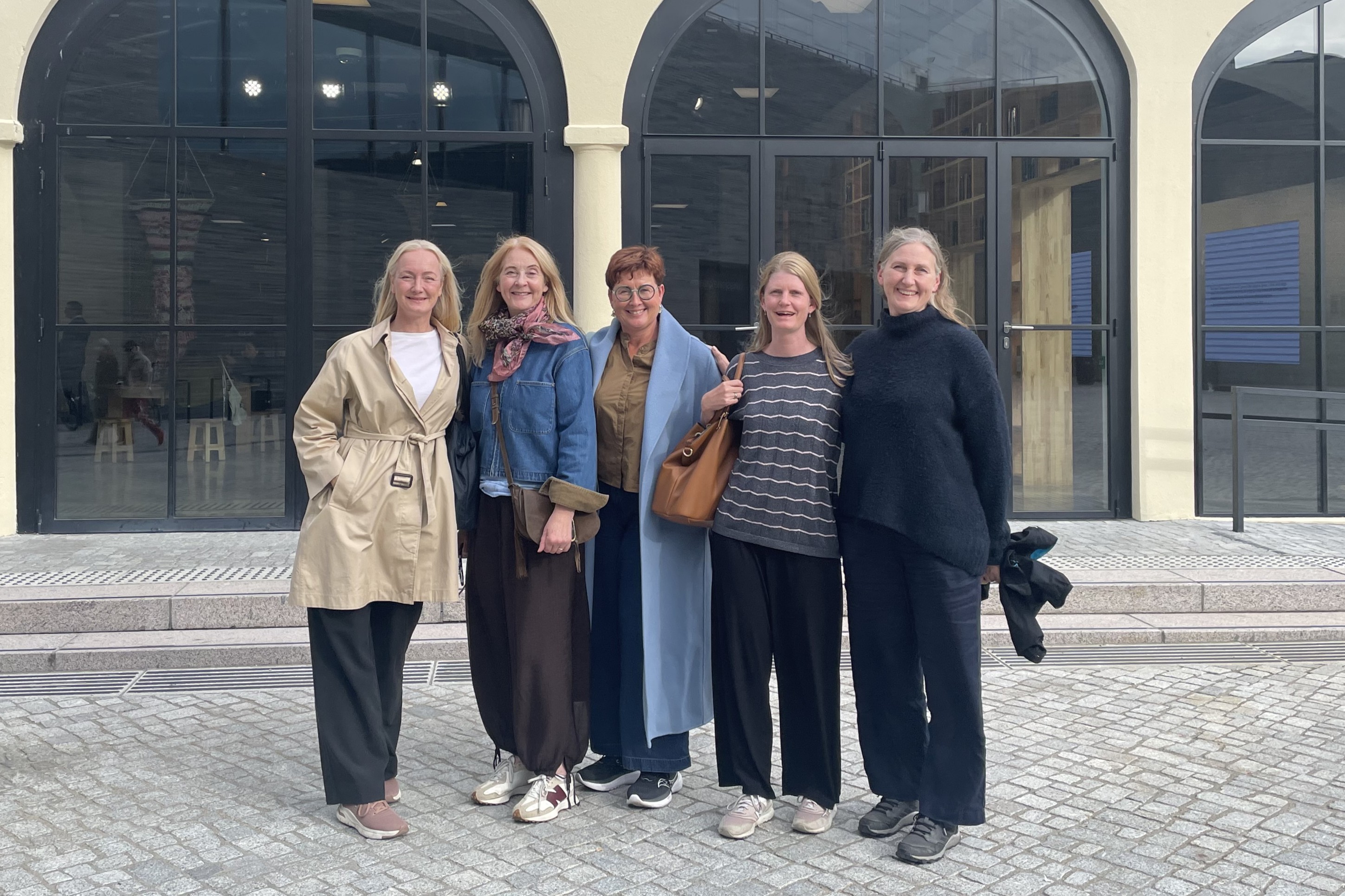 En gruppe kvinner poserer for et bilde utenfor en bygning