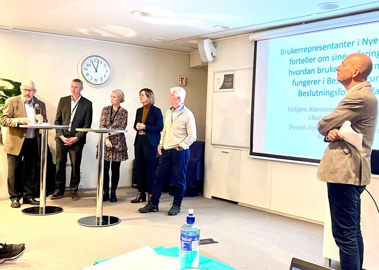En gruppe mennesker som står foran en skjerm