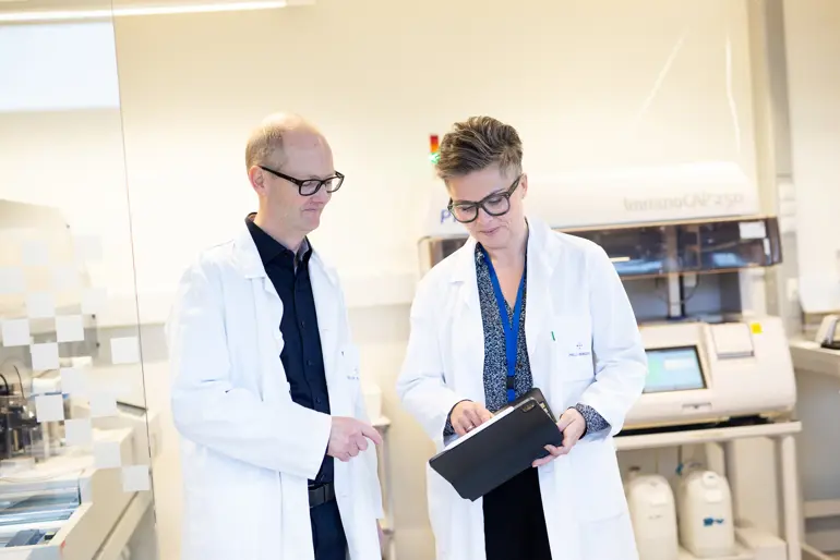 Mann og kvinne i labfrakk som ser på en skjerm