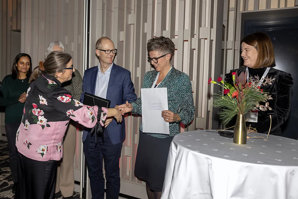 En gruppe mennesker som står ved siden av et bord med blomster