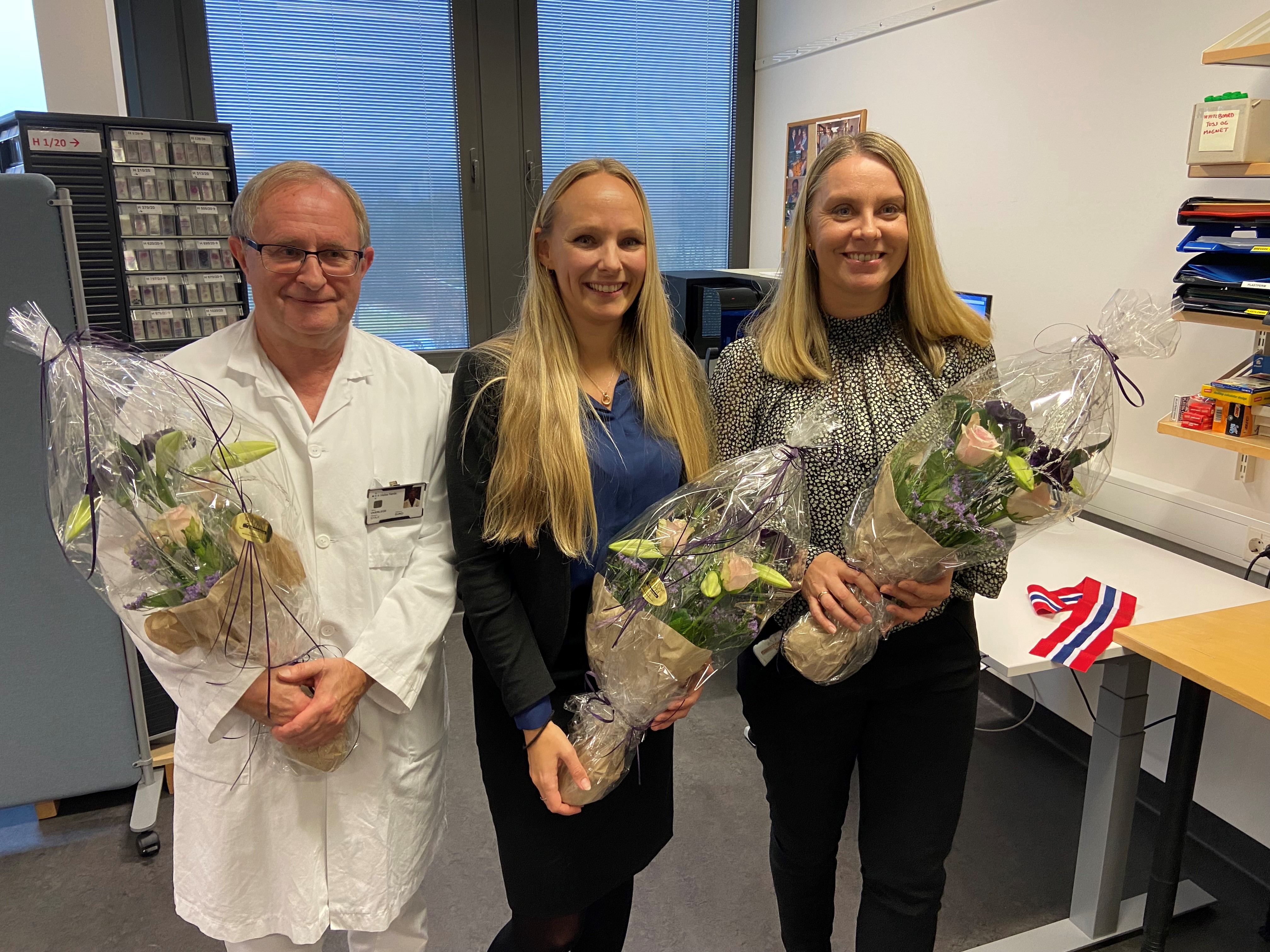1 mann og 2 kvinneer med hver sin blomsterbukett. Foto.